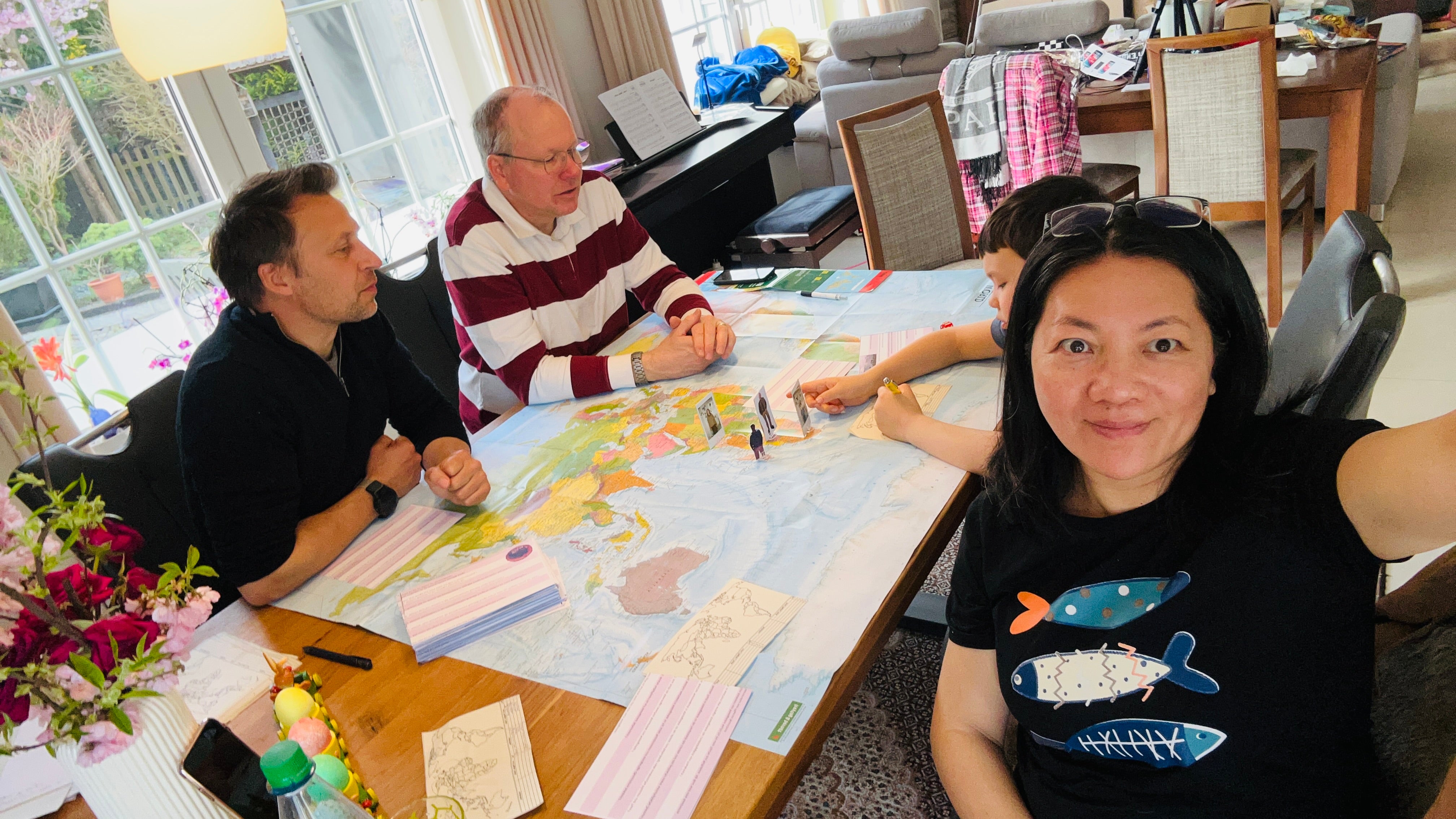 Familie spielt WELTKARTE Geografie-Brettspiel auf echter Weltkarte
